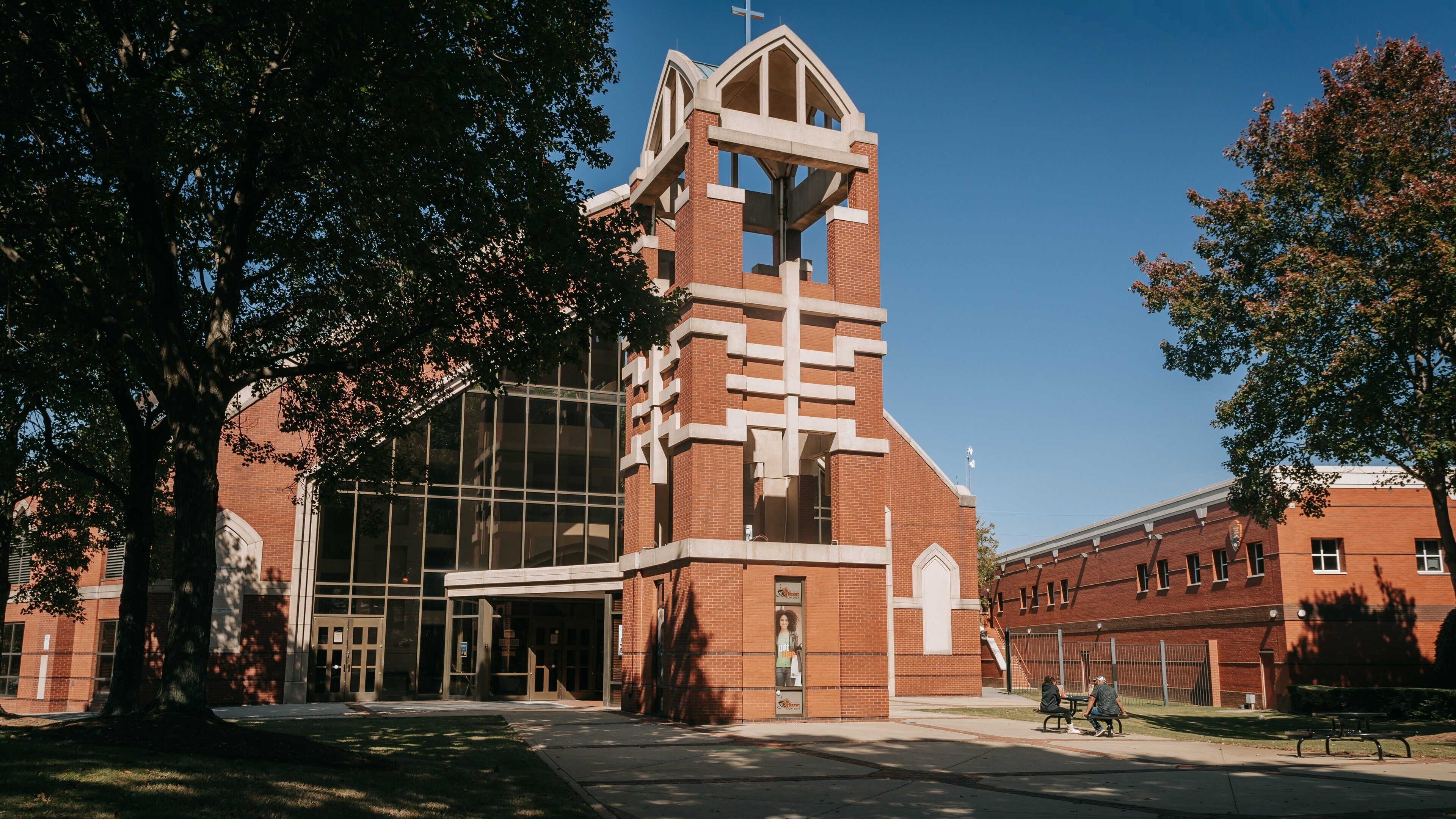 Een kerk met een hoge klokkentoren en een ruime glazen ingang.