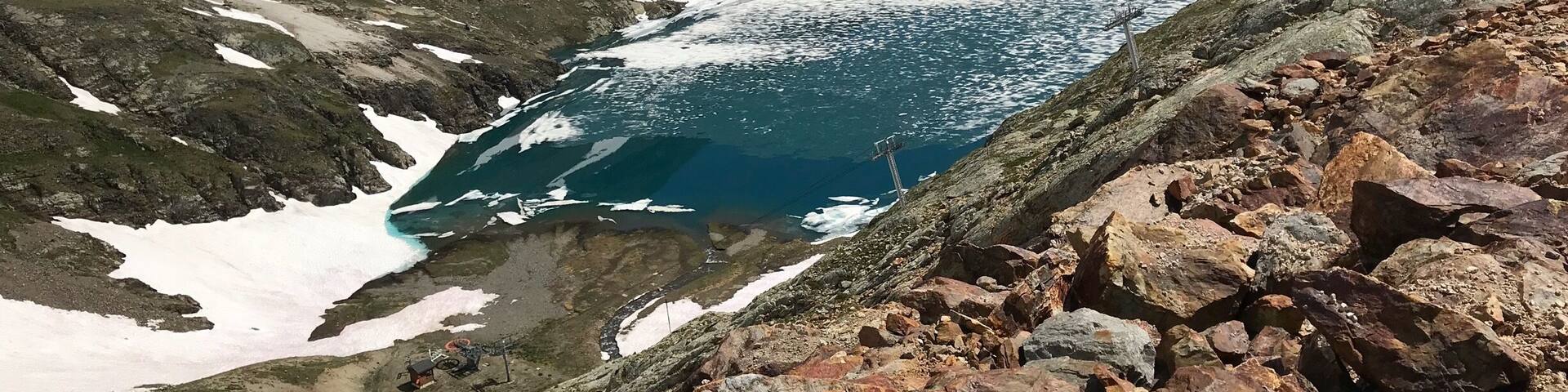 High above the mountain town of Alpe DâHuez. In summer times when the snow melts it leaves amazing blue lakes with frozen snow floating across the top.