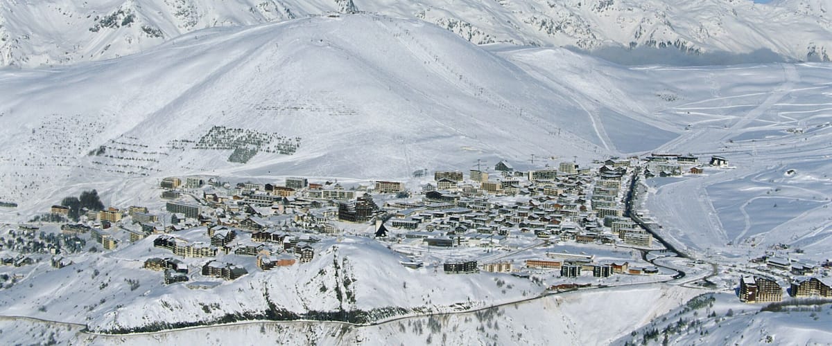 A snow-covered mountain town with buildings and a clear blue sky.