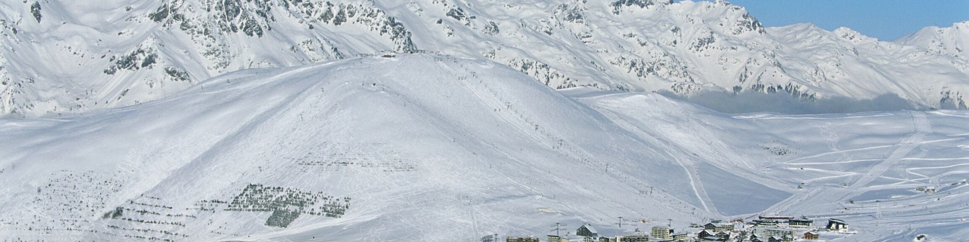 A snow-covered mountain town with buildings and a clear blue sky.