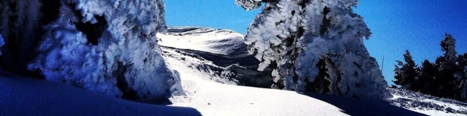 A snow-covered mountain landscape with distinct snow formations and a clear blue sky.