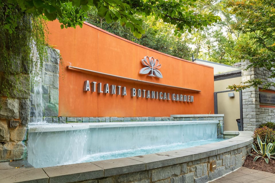 The Atlanta Botanical Garden entrance with a stone wall and a water feature.