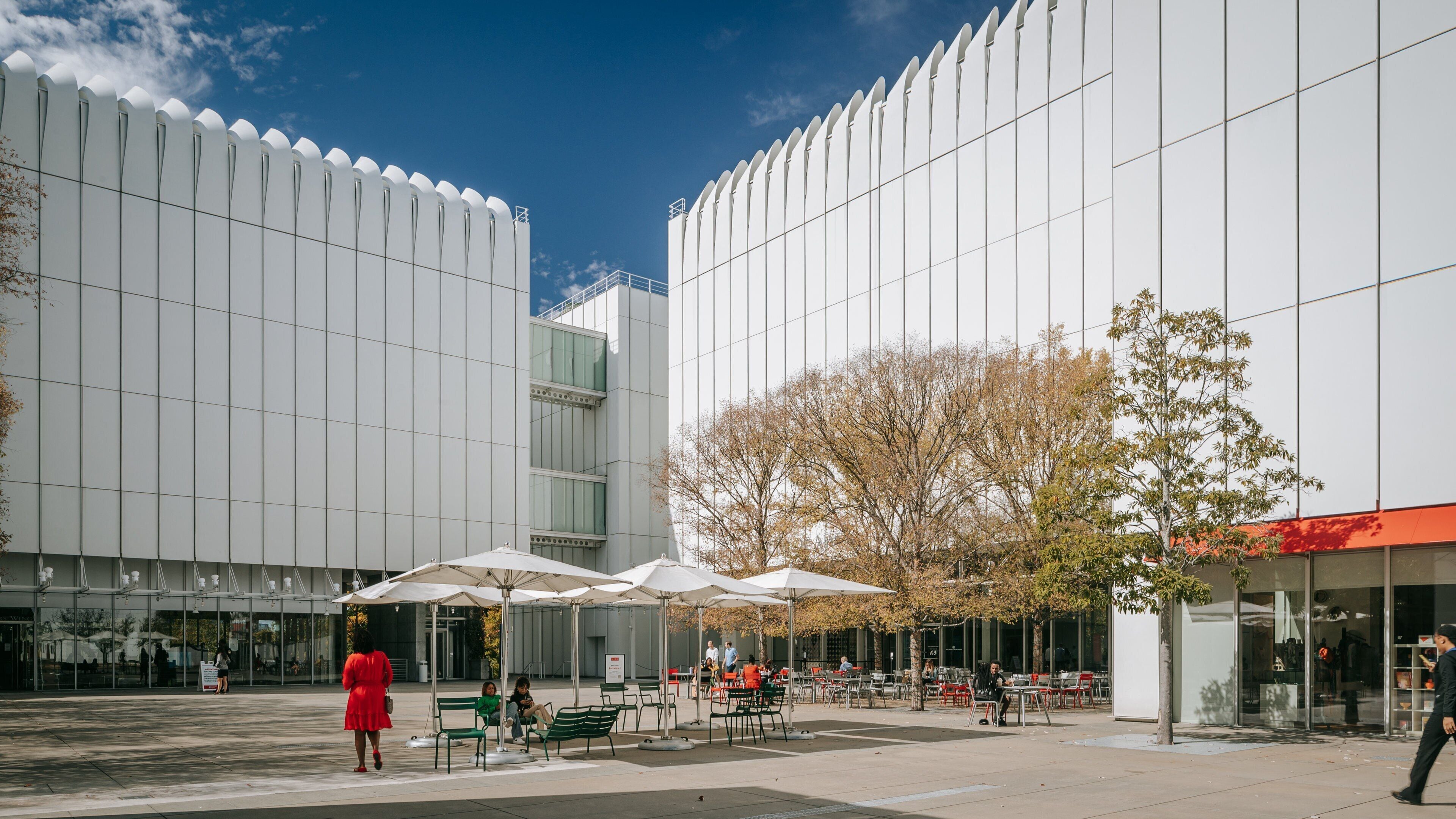 A modern building with a white facade and a tree-lined courtyard.