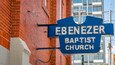 A blue sign with white lettering that reads "EBENEZER BAPTIST CHURCH" mounted on a brick wall.