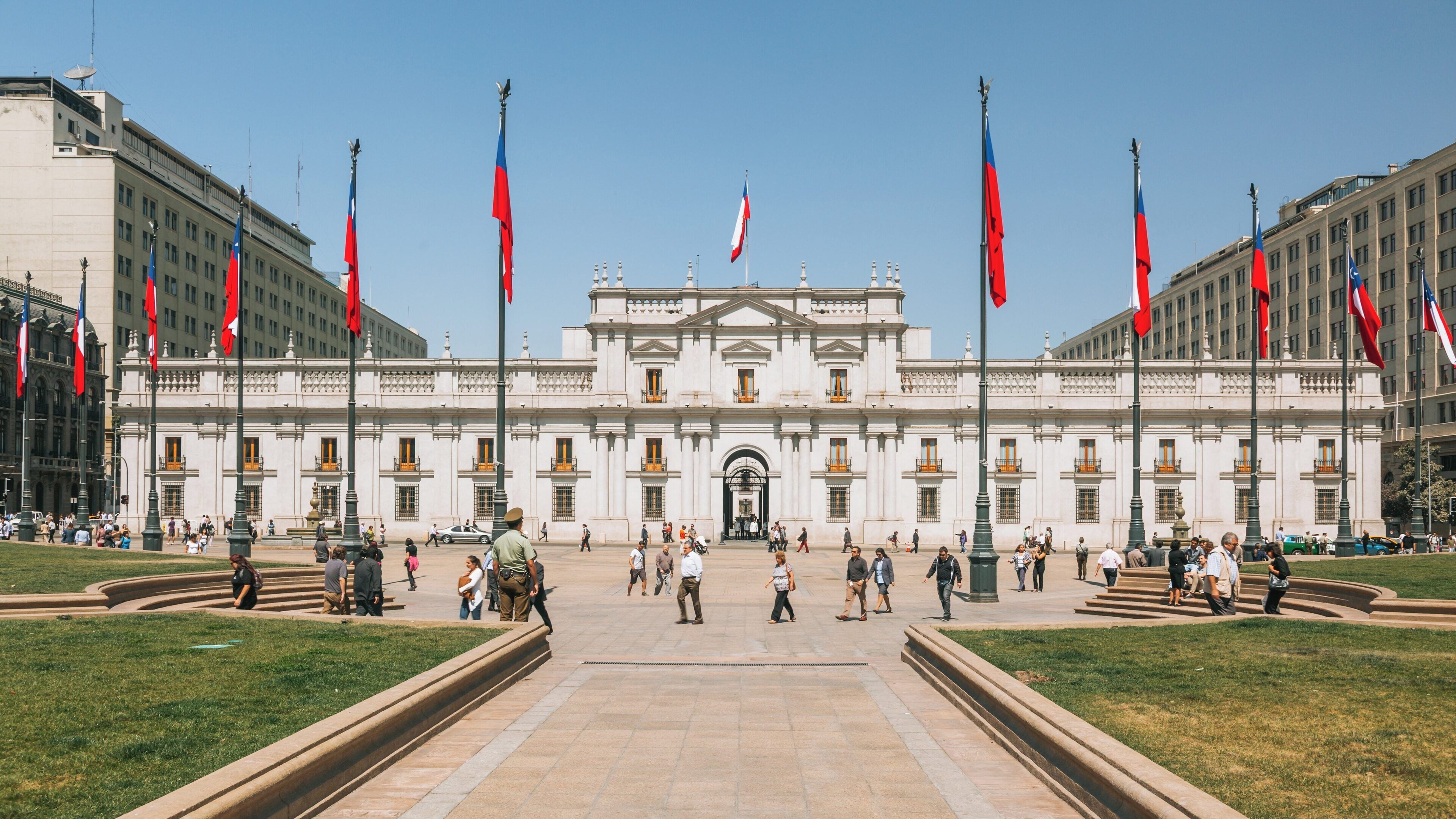 Palacio de la Moneda in Santiago Center showcasing vibrant flags and visitors during a clear day