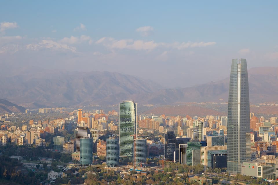 A cityscape with modern skyscrapers and mountains in the background.