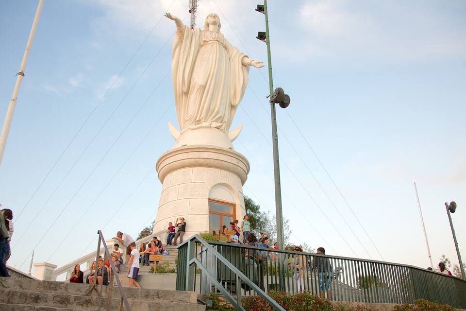 Una estatua blanca grande sobre un pedestal, rodeada de gente.