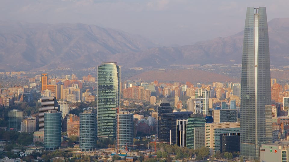 Paisagem urbana com arranha-céus modernos e montanhas ao fundo.