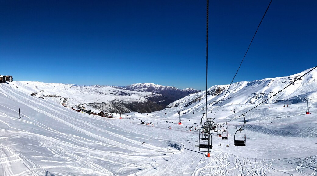 Panorama view of ski resort, slope, people on the ski lift, skiers on the piste among white snow in Valle Nevado near Santiago de Chile. Winter season extreme sports in South America.