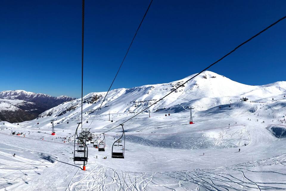 A snow-covered mountain with ski lifts and skiers.