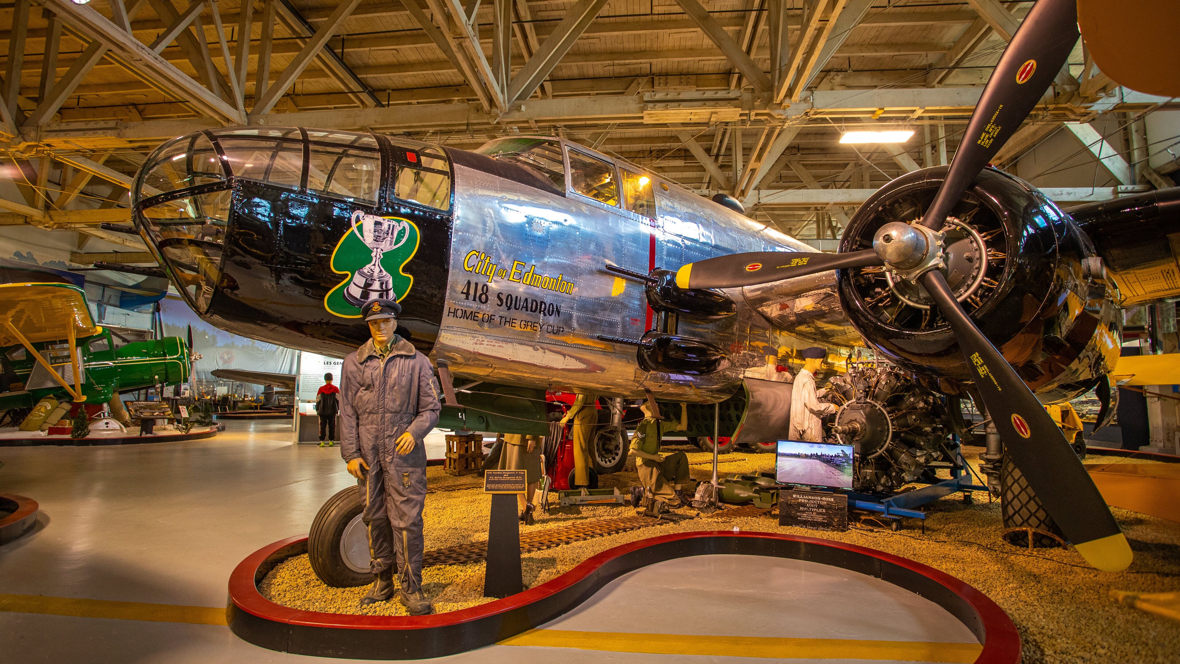 A vintage aircraft with "City of Edmonton" and "Home of the Grey Cup" text, a pilot mannequin, and a propeller.