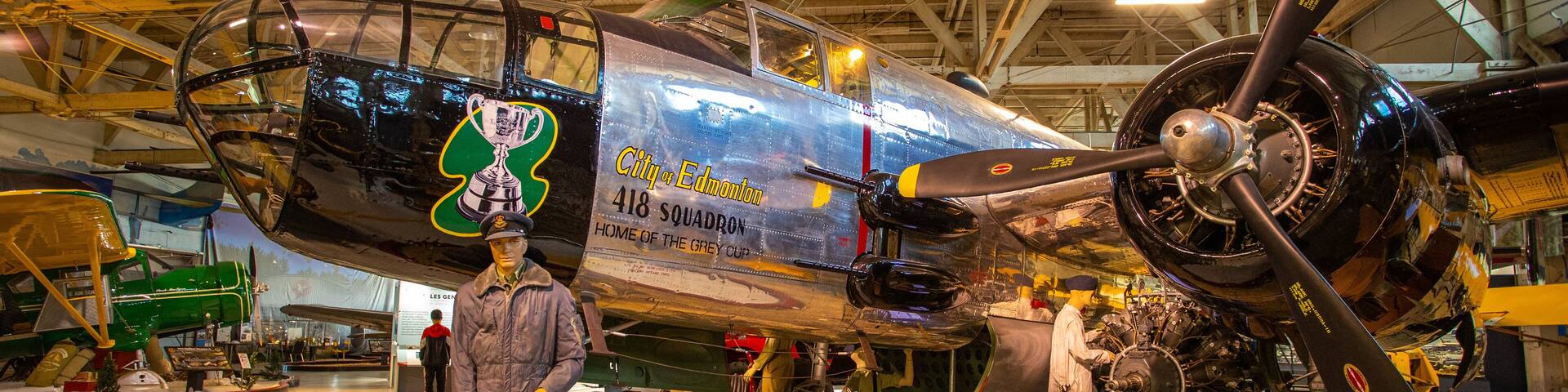 Un avion d’époque portant les inscriptions « Ville d’Edmonton » et « Ville hôte de la Coupe Grey », un mannequin de pilote et une hélice.