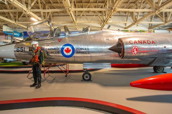 Uma aeronave militar prateada com o número 65 e as palavras “Forces Armee” e “Canada” em sua lateral.