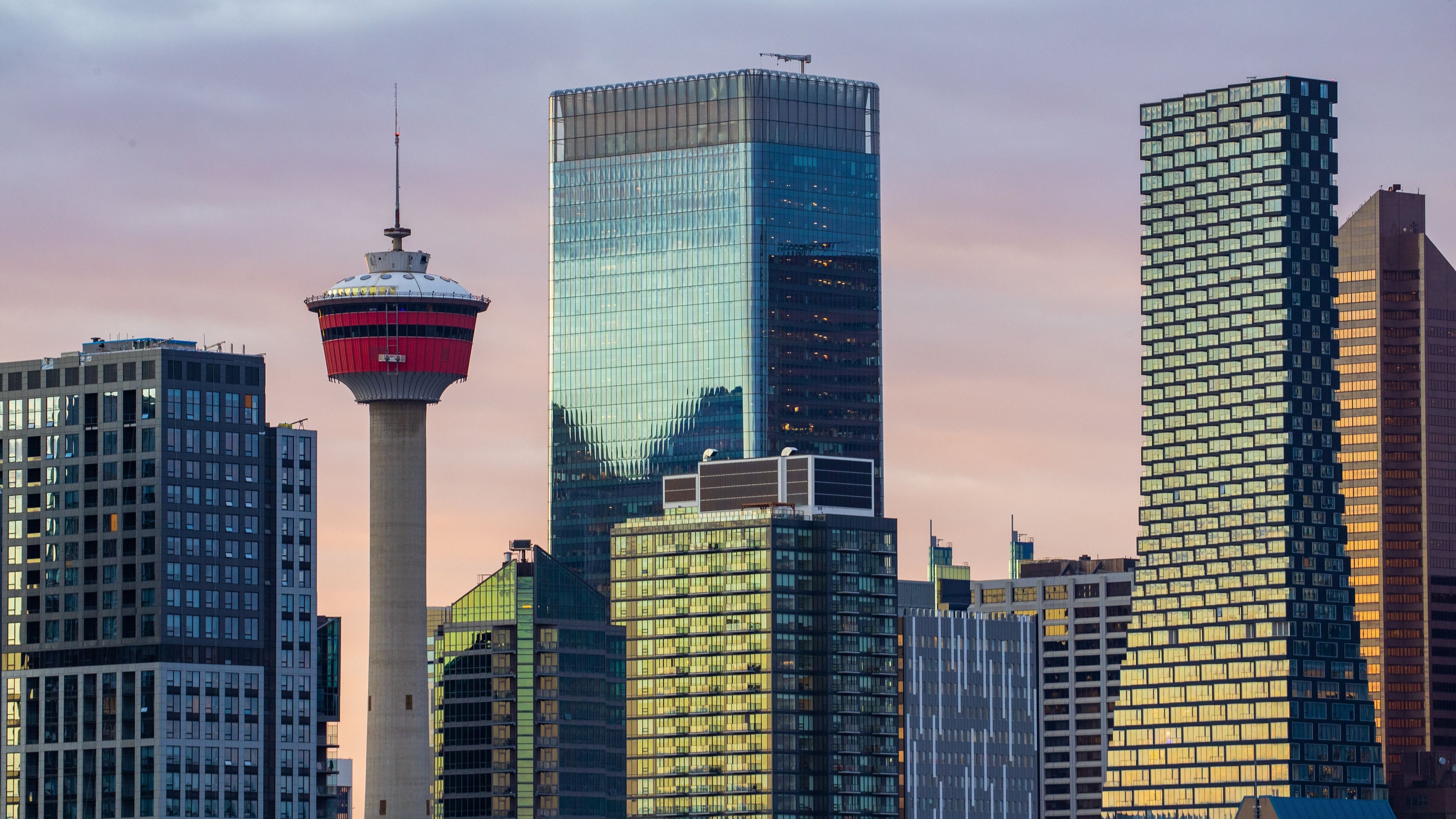 Scotiabank Saddledome which includes a high rise building, a city and a sunset