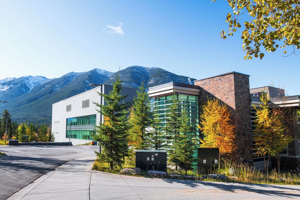 A modern building complex with a mountain backdrop.