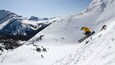 Een skiër in de lucht die een sprong maakt op een besneeuwde berghelling.