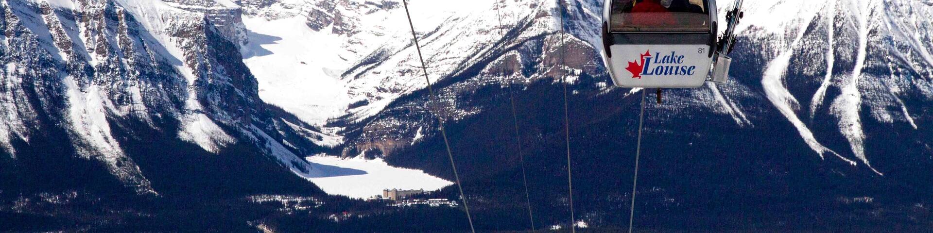A cable car labeled "Lake Louise" ascending a snowy mountain.