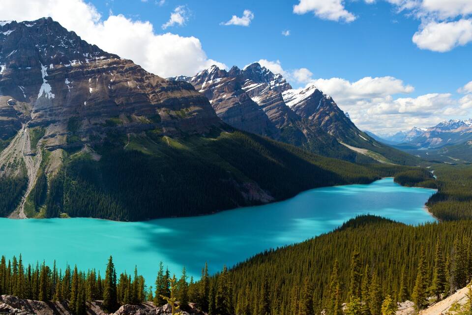 Una cordillera con un lago turquesa rodeado de bosques densos.