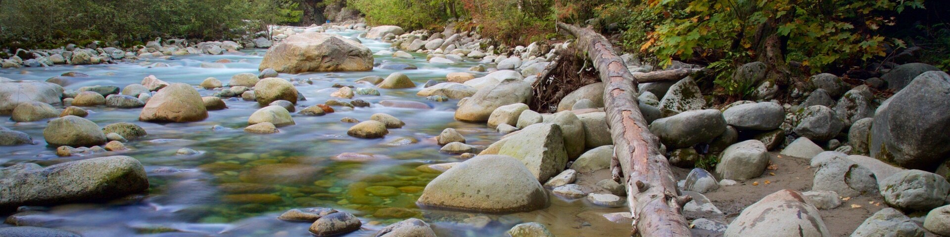 Um rio com águas cristalinas, rodeado por rochas e árvores.