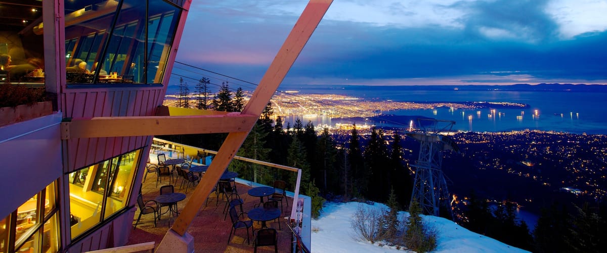 A high vantage point overlooking a cityscape at dusk with illuminated buildings and a bridge.