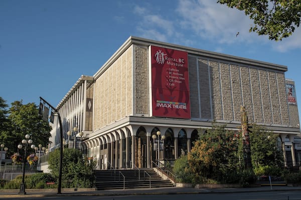 Un grand bâtiment orné d’une bannière rouge faisant la publicité du Royal BC Museum et de son cinéma IMAX.