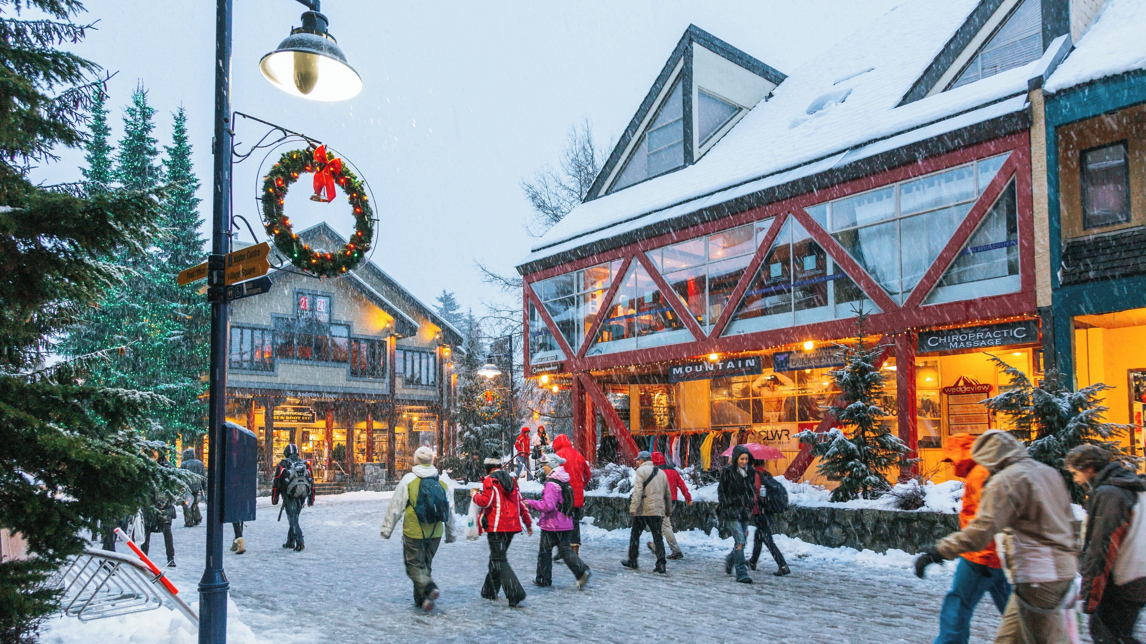 People enjoy winter activities in Whistler Village surrounded by festive decorations and snow-covered surroundings in British Columbia, Canada