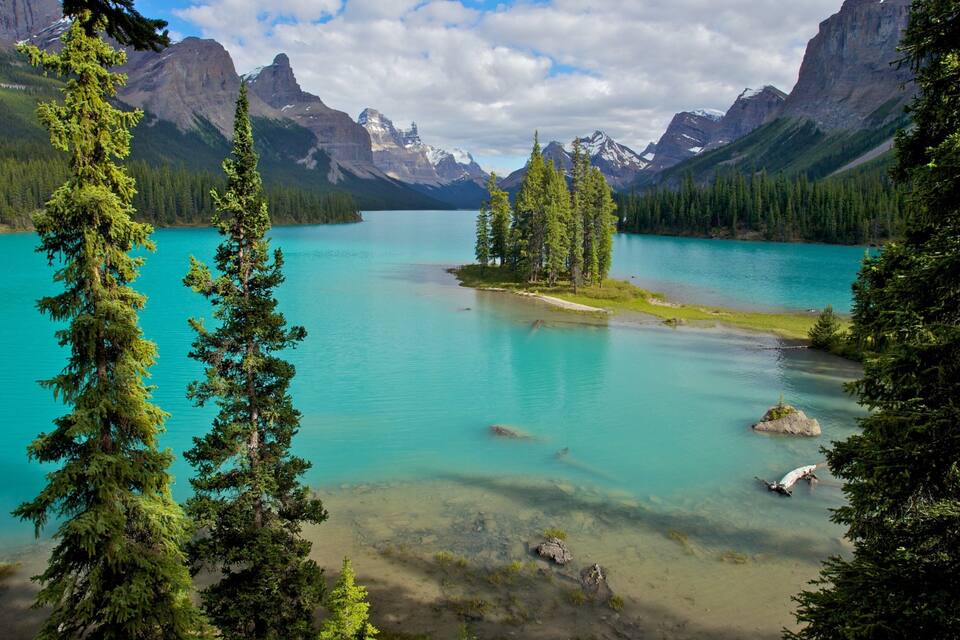 A turquoise lake surrounded by mountains and coniferous trees.