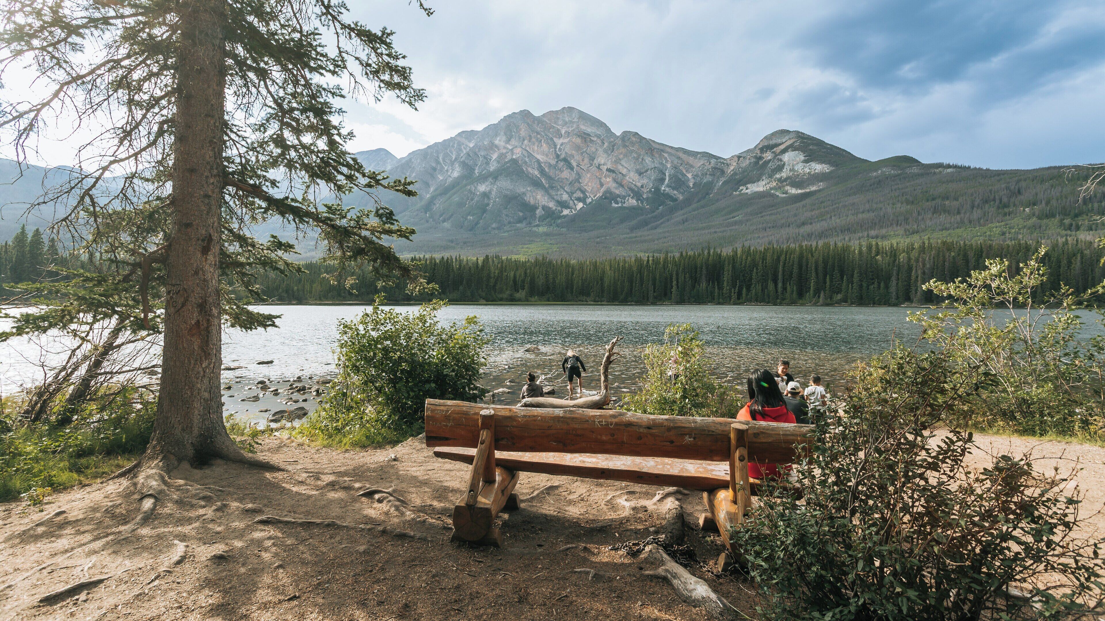 Visitors explore the serene shores of Pyramid Lake in Jasper, Alberta, surrounded by majestic mountains and reflecting waters