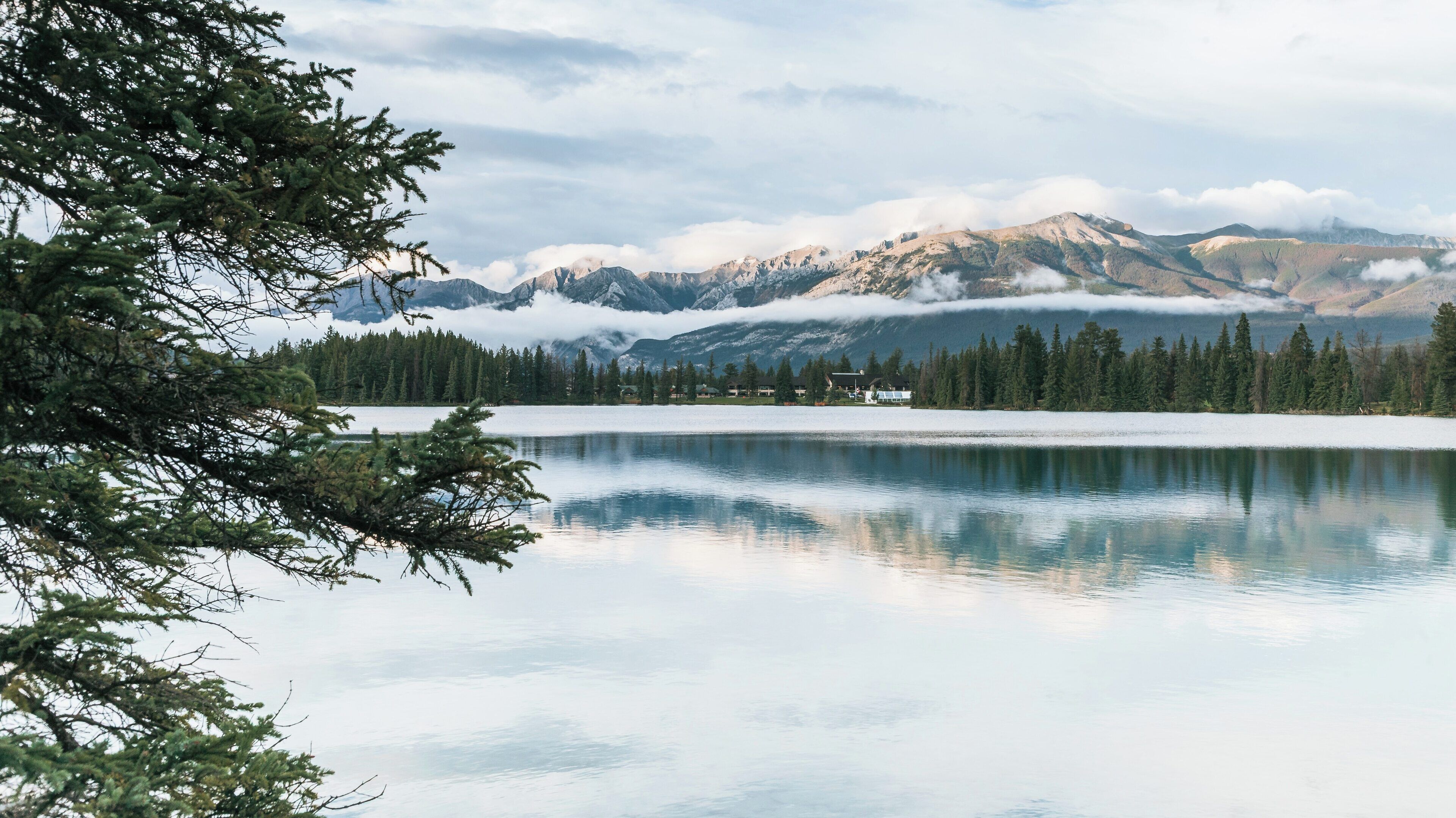 Lac Beauvert in Jasper, Alberta reflects the serenity of nature with majestic mountains and calm waters in early morning light