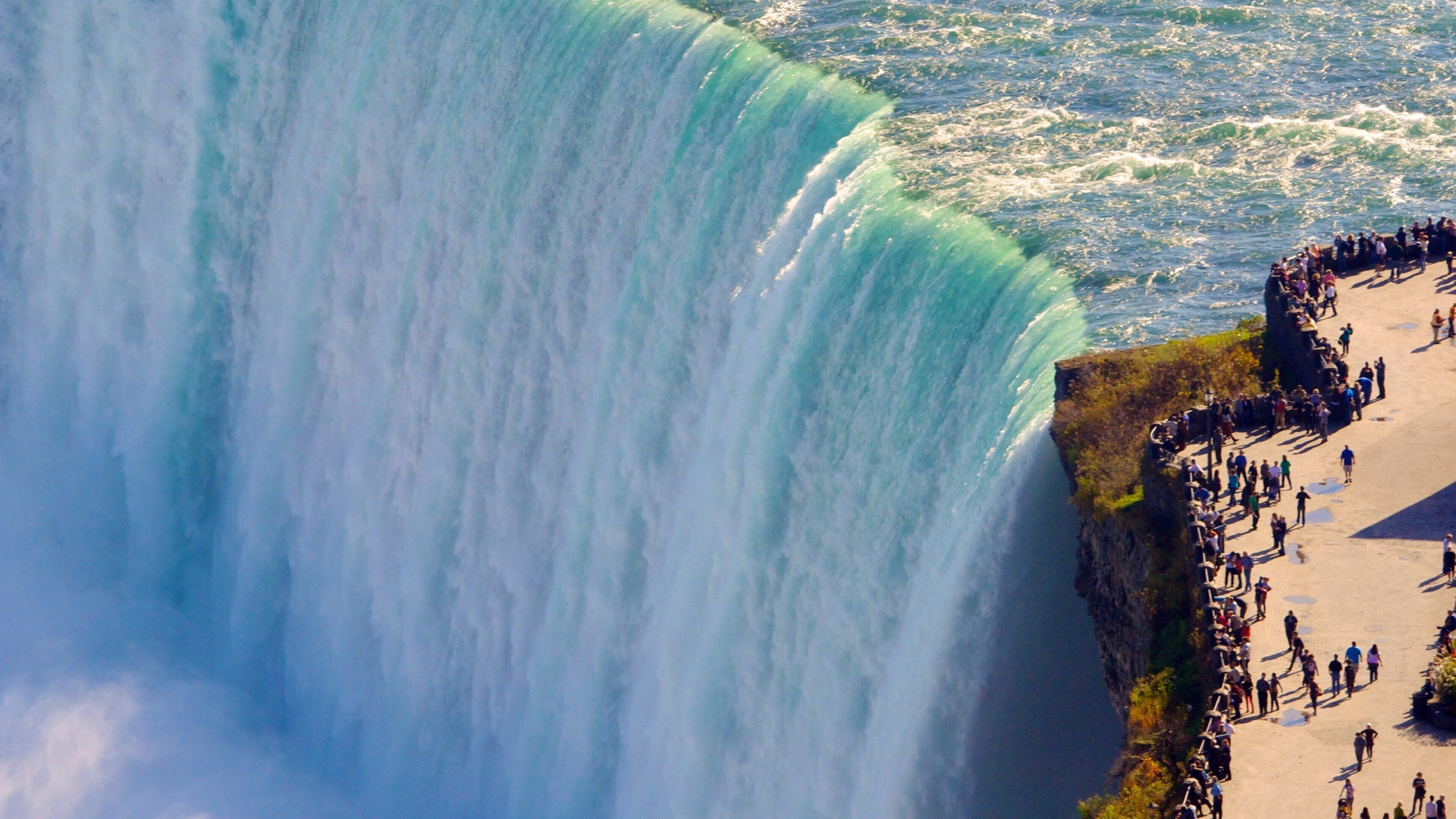 A large waterfall with a viewing platform and people gathered around.