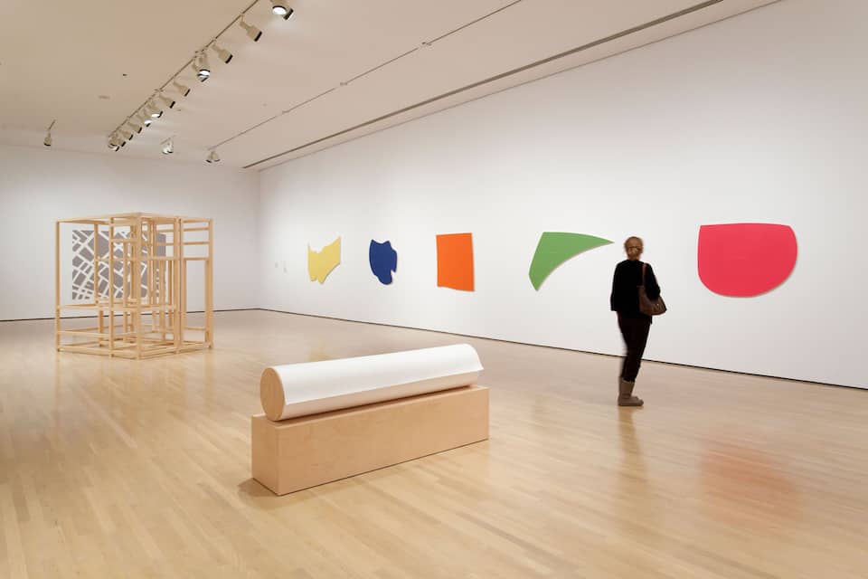 Une galerie d’art où l’on peut admirer des sculptures en bois et des peintures géométriques aux couleurs vives, accrochées aux murs.