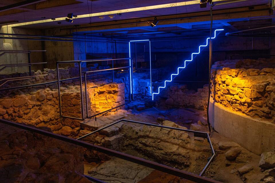 An archaeological site with exposed ruins and a neon-lit staircase.