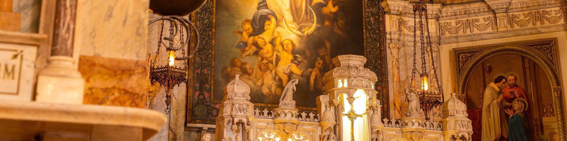 An ornate church interior with a central religious painting, intricate ceiling, and detailed architectural elements.