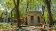 Ein Park mit einem Kiosk, roten Sonnenschirmen und Bänken.