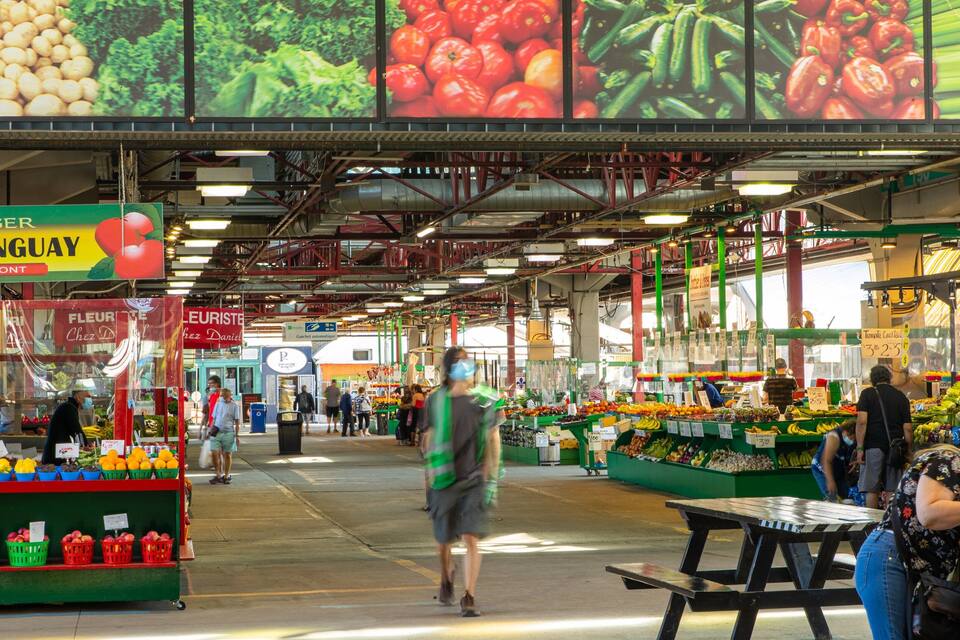 An indoor market with various stalls selling fruits and vegetables.