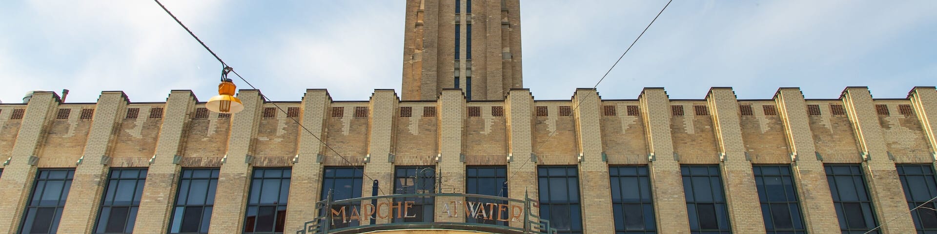 A large brick building with a clock tower, a balcony, and a sign that reads "CHEMICAL WAREHOUSE".