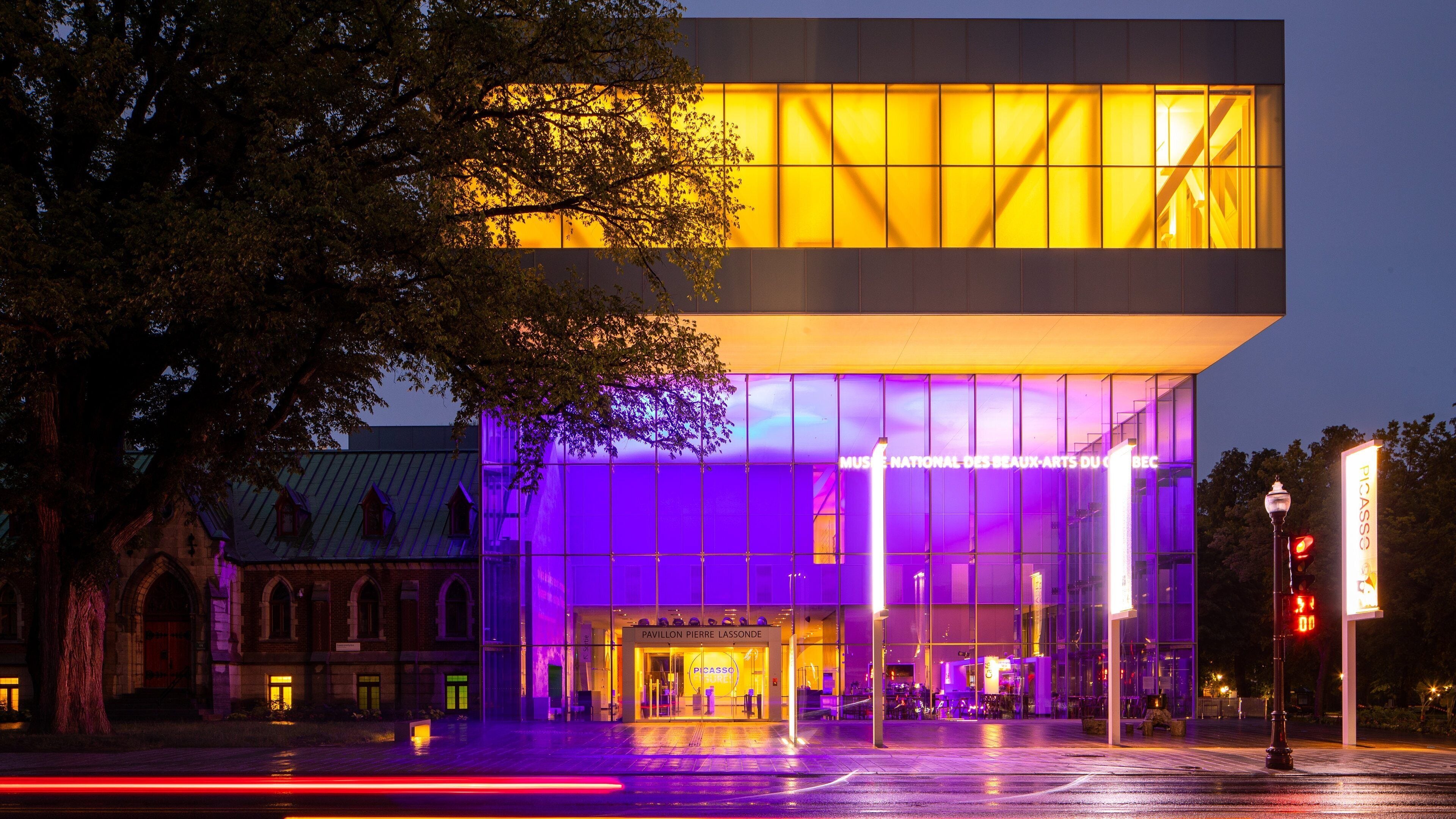 A modern building with illuminated windows and a sign for the Picasso Museum.