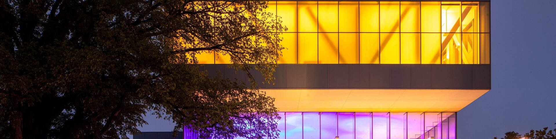 A modern building with illuminated windows and a sign for the Picasso Museum.