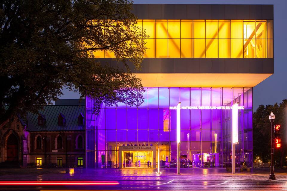 A modern building with illuminated windows and a sign for the Picasso Museum.