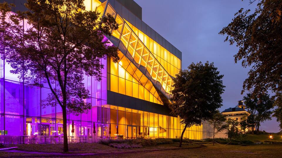 A modern building with a glass facade and a distinctive triangular structure.