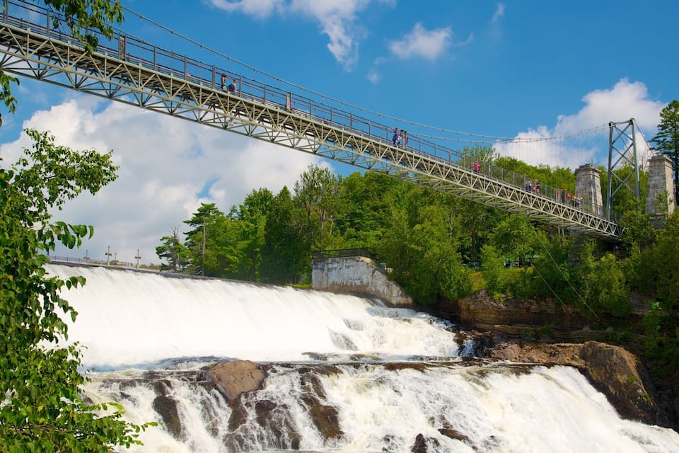 A suspension bridge over a waterfall surrounded by trees.