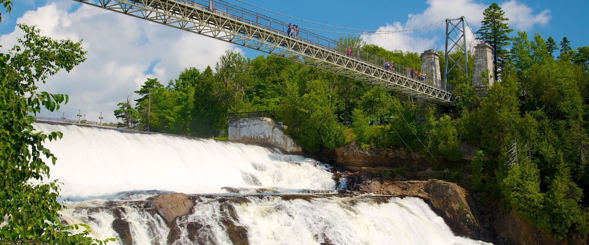 A suspension bridge over a waterfall surrounded by trees.