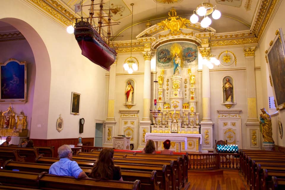 Ein prunkvolles Kircheninnere mit großem Altar, goldenen Verzierungen und einem Schiffmodell.