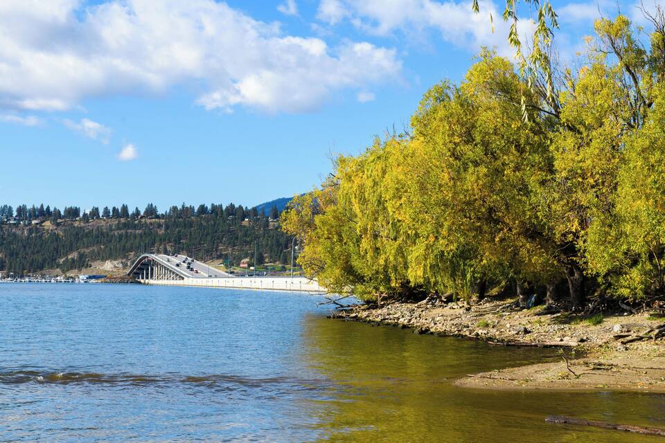 A bridge over a river, surrounded by autumn trees and a hilly landscape.