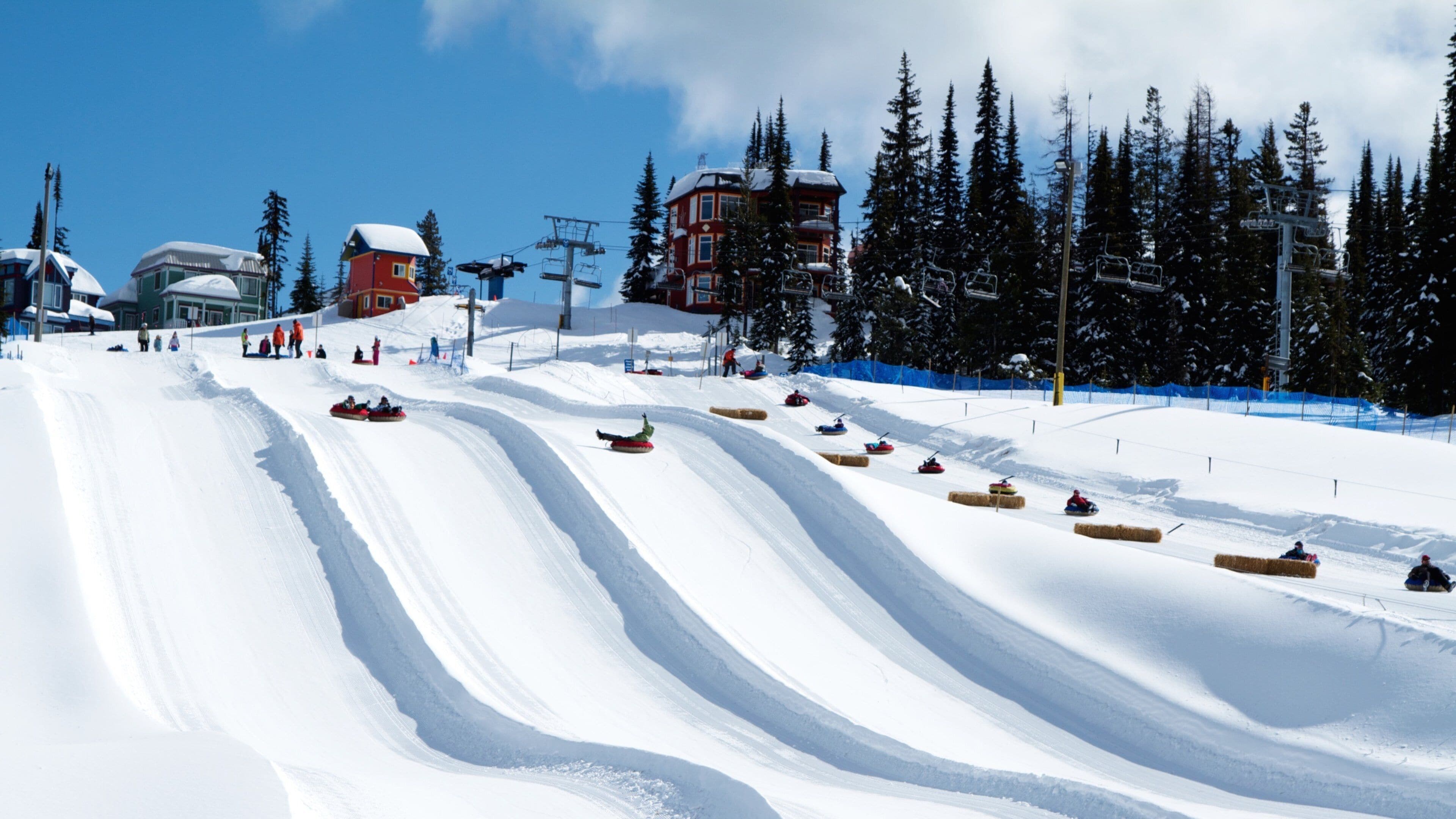 Estación de esquí Silver Star mostrando nieve y llantas inflables para deslizarse por la nieve y también un pequeño grupo de personas