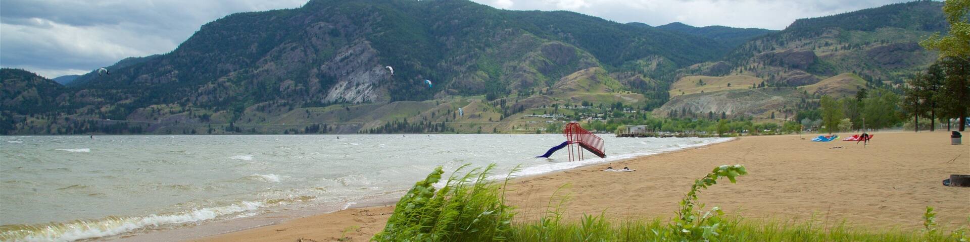 A beach with a red chair, a sandy shore, and mountains in the background.