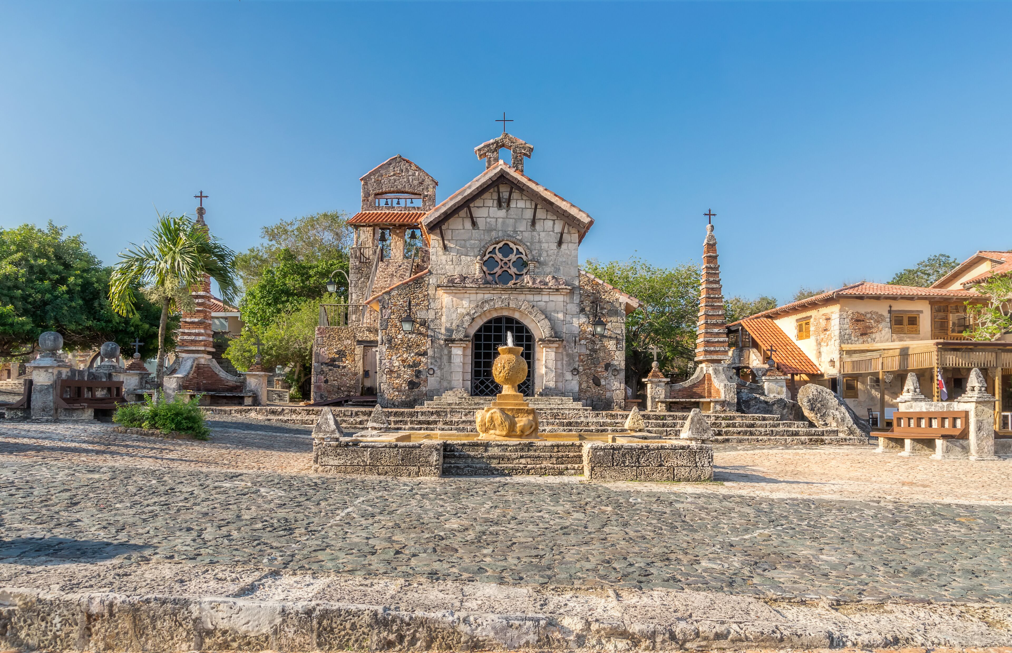 A historic church with a stone facade, a bell tower, and a fountain in the foreground.