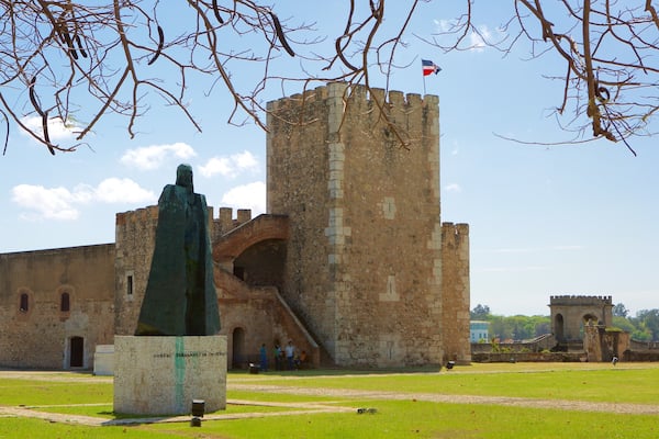 Un château historique, avec une statue devant, un drapeau au sommet et un ciel dégagé.