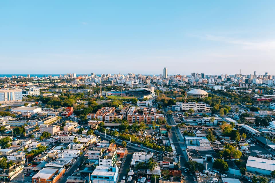 Paisagem urbana com mistura de edifícios residenciais e comerciais, um estádio em destaque e vista clara da costa.
