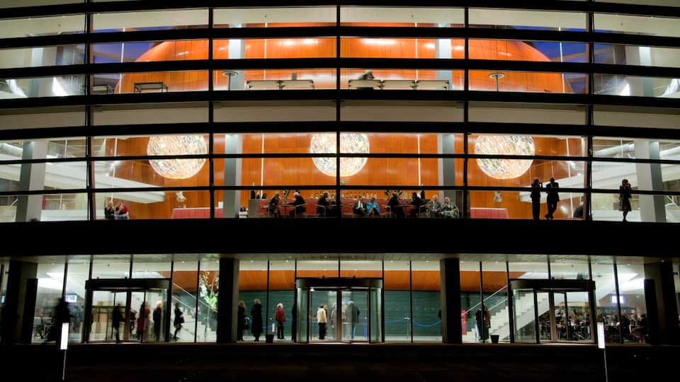 A modern building with large glass windows and a central spherical light fixture.